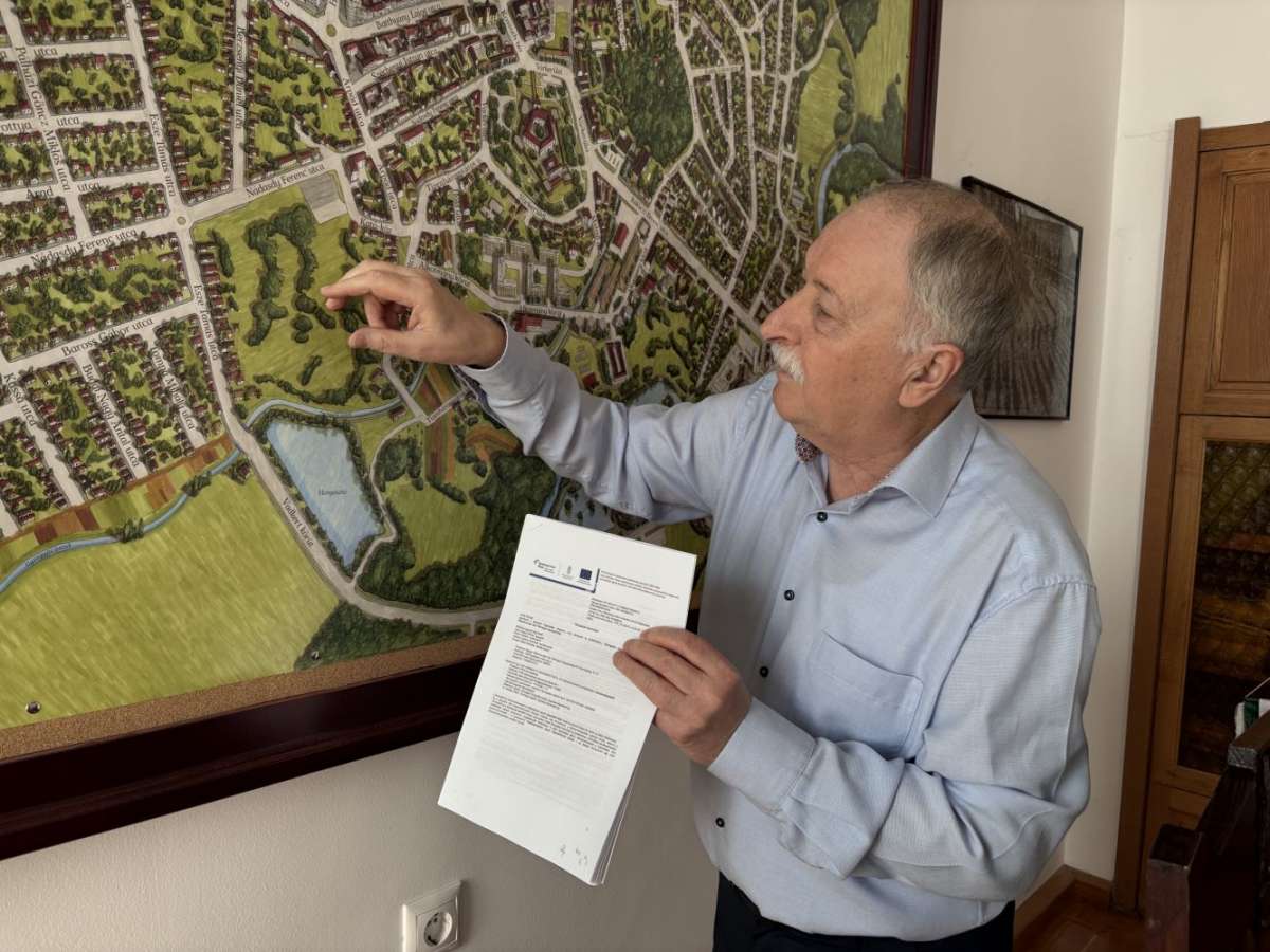 Kondora István az aláírt támogatási szerződést és a szabadidőpark helyét mutatja